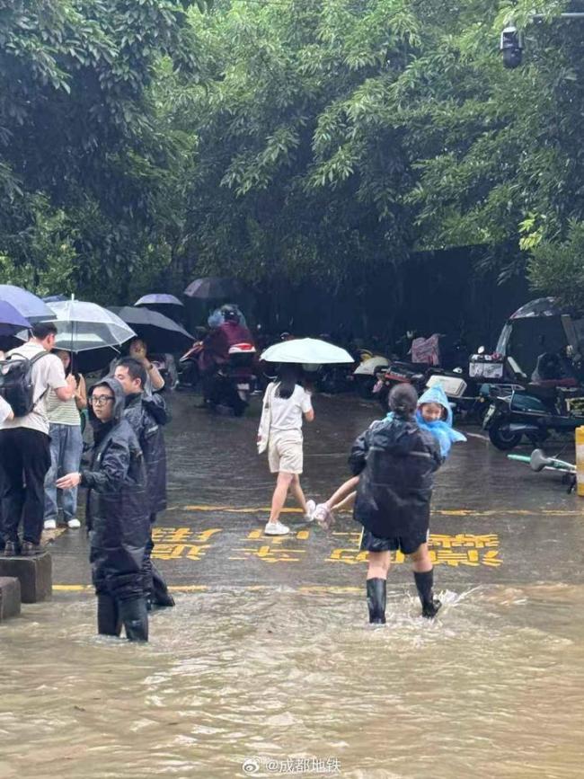 成都地铁口工作人员为乘客发雨衣