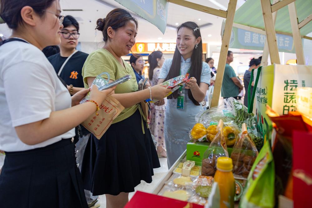  6月28日，工作人员在泰州市海陵区万达广场“跟着苏超游徐州”徐州文旅（泰州）推介会上向消费者推介文旅商品。（汤德宏 摄）