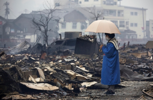 2024年1月1日,日本石川县能登半岛发生规模7.6强震,引发海啸和大规模火灾。 一名妇女站在被大火烧毁的轮岛市早市前。 (美联社) 2024年1月1日,日本石川县能登半岛发生规模7.6强震,引发海啸和大规模火灾。 一名妇女站在被大火烧毁的轮岛市早市前。 (美联社)