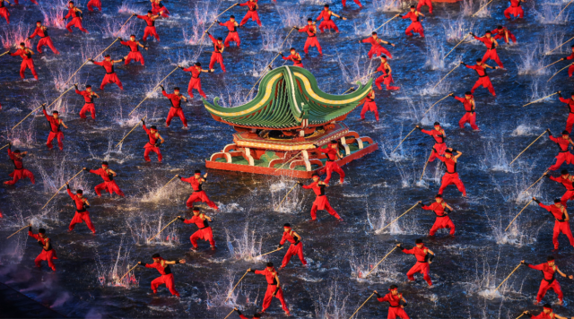  开幕式文体展演第二章《同心同缘》，棍术表演者踏入中央水域，粼粼波光映照着翻飞的棍影，光影交错，气势如虹。图源：新华社