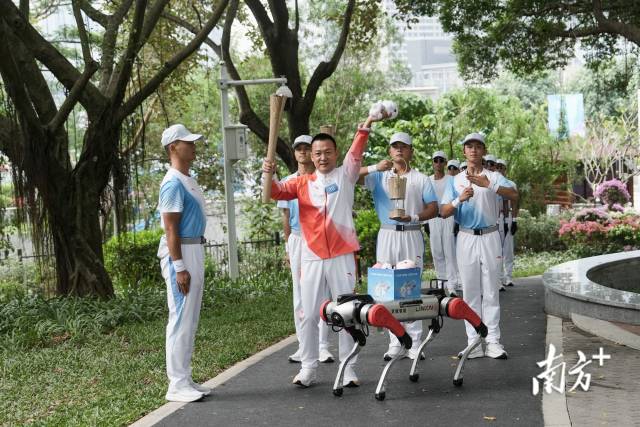 11月2日上午，十五运会火炬传递活动上“机器狗”现身深圳，将全运会吉祥物交给火炬手。