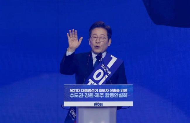 李在明穿防弹衣外套西装演讲,向欢呼观众跪地磕头,身旁两位黑衣警卫高度警惕